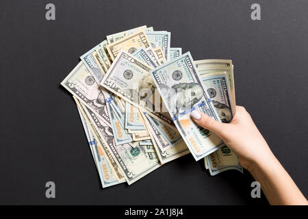 Vista superior de las manos de una empresaria contando cien y diferentes billetes de dólar sobre fondo de colores. Concepto de riqueza y éxito. Foto de stock