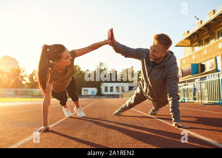 Pareja joven haciendo pushups en el estadio