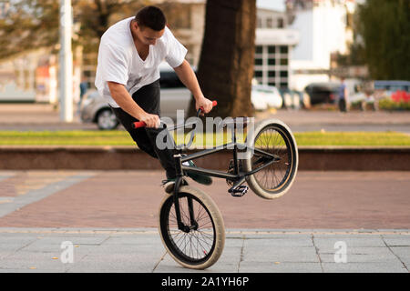 El chico de la bicicleta acrobática, gira la moto en la rueda delantera, alrededor de su eje. Foto de stock
