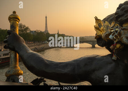 Estatua de ninfas con candados en el puente Alexandre III con la Torre Eiffel en el fondo al atardecer en París