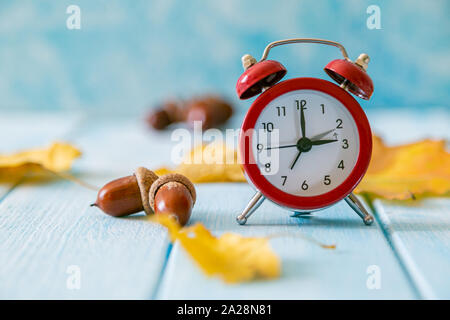 Cambio de horario de otoño concepto - despertador rojo sobre fondo de madera