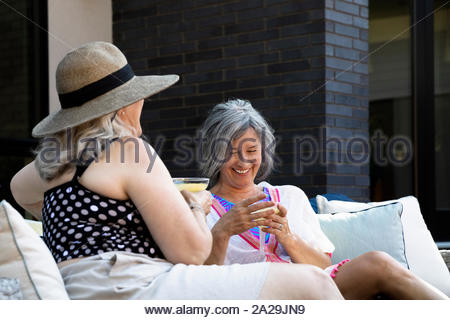 Feliz, despreocupado de las mujeres mayores amigos bebiendo margaritas en el patio de verano