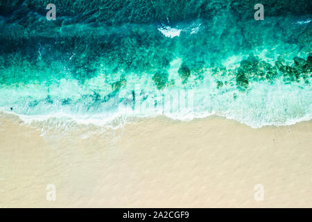 Vista aérea mirando hacia abajo en una cala tranquila con grandes olas rompiendo en la playa Foto de stock