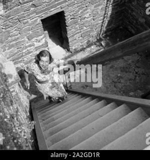 Eine junge Frau auf einer steilen Stiege bei einer Besichtigung, Österreich 1930er Jahre. Una joven mujer en una escalera woddenn haciendo una excursión, Austria 1930.