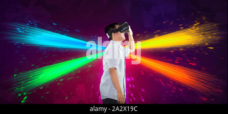 Vista lateral de medio cuerpo shot de un adolescente experimentando y disfrutando de la realidad virtual con tecnología de ráfaga de fibra conceptual colorido telón de fondo. Foto de stock