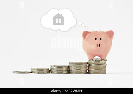 Hucha de soñar con la compra de una casa en la recaudación de los montones de monedas - Concepto de ahorrar dinero para comprar una casa