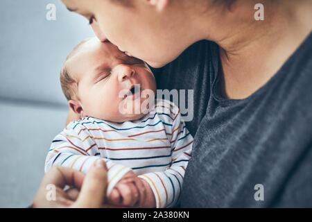 La madre con el recién nacido. Mujer besando a su hijo de 4 días en casa.