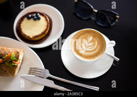 Desayuno con café capuchino con arte y sándwich de salmón Foto de stock