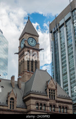La torre del reloj y la fachada de la histórica Old City Hall en Toronto Ontario contra un fondo de edificios modernos.