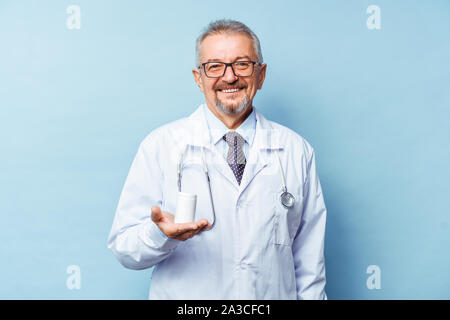 Hombre caucásico médico sosteniendo una botella de píldoras sobre fondo blanco. Foto de stock