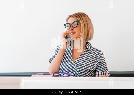 Pensativo joven atractivo profesor con gafas ropa formal en la enseñanza en clase y hacer un examen. sentados cerca de pizarra.