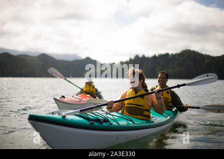 Feliz pareja adulta media en kayak en un lago con su hijo adolescente. Foto de stock