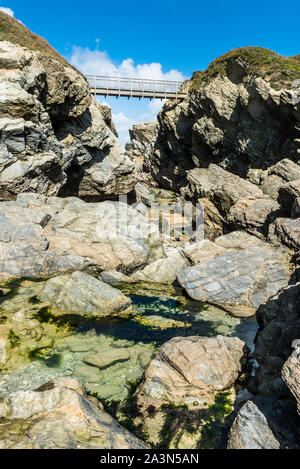 El puente que une la tierra firme con la isla de Porth en Porth Beach en Newquay en Cornualles. Foto de stock