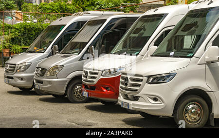 En Positano, Italia - Agosto 2019: fila de pequeños autocares Mercedes estacionado en la ciudad de Positano en la Costa Amalfitana de Italia. Foto de stock
