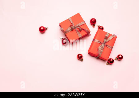 Primer plano de rojos pequeños regalos con cinta de oro sobre fondo de color rosa. Fondo de Navidad. Concepto minimalista. Sentar planas. Vista desde arriba.