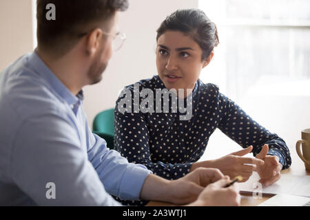 India mentor hembra a macho compañero trabajador hablando en Office Foto de stock