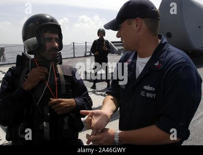 Fire Controlman 1st Class Michael Davidson, asignado al USS Cowpens (CG 63), habla con un miembro de una visita, junta, búsqueda e incautación (VBSS) Equipo de INS Mysore. Foto de stock