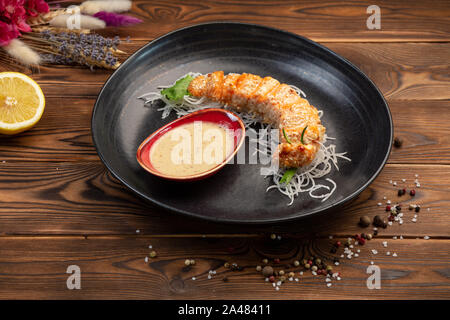 Rodajas de salmón horneado en la miga de pan con la salsa caliente sobre una almohada daikon Foto de stock