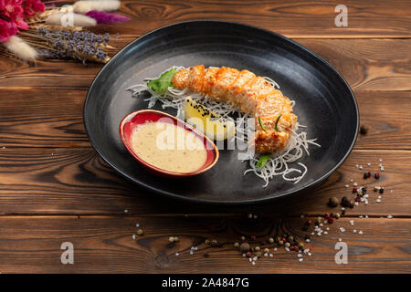 Rodajas de salmón horneado en la miga de pan con la salsa caliente sobre una almohada daikon Foto de stock
