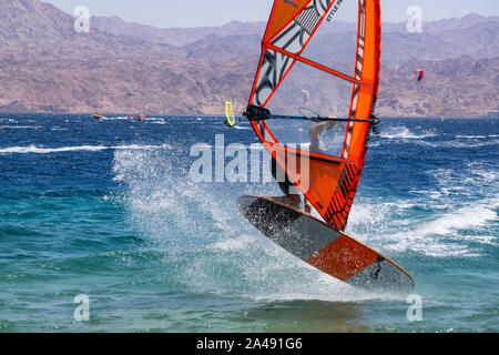 Eilat, Israel - 12 de abril de 2019: el hombre es aventurero disfrutar de deportes acuáticos, windsurf, en el Mar Rojo durante un día soleado. Foto de stock