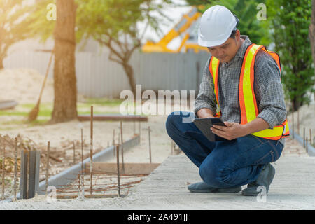 Ingeniería, usar un casco y sosteniendo las tabletas, sentarse a revisar la estructura del corredor en el parque