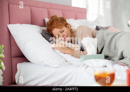 Rizado mujer pelirroja durmiendo después de tomar las píldoras Foto de stock