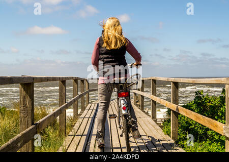 Sylt mujer con bicicleta en un paseo marítimo