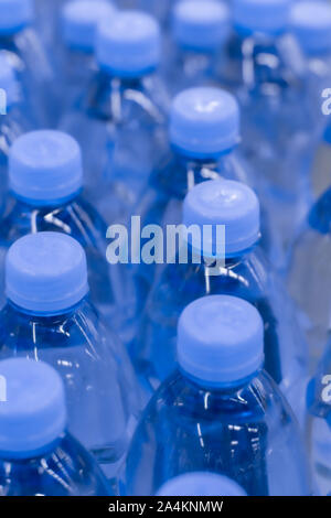Desenfoque de fondo, agua potable pura en botellas de plástico. Tapones de botella azul, vista superior. Muchas bebidas botellas en un supermercado Foto de stock
