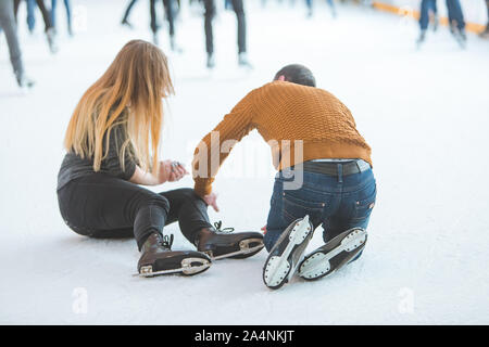 Mujer caen hacia abajo mientras patinaba ayudando a su hombre. Foto de stock