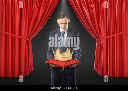Empresario con corona de oro sobre la almohada rojo sobre rojo fondo de cortina Foto de stock
