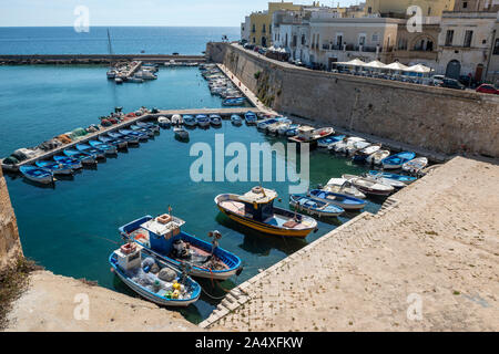 Barcos amarrados en el puerto, junto a la muralla de la ciudad vieja en la ciudad vieja de Gallipoli, Apulia (Puglia) en el sur de Italia