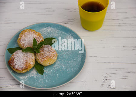 Cheesecake sobre una placa de color azul y amarillo taza de café de whis sobre un fondo de madera ligera Foto de stock
