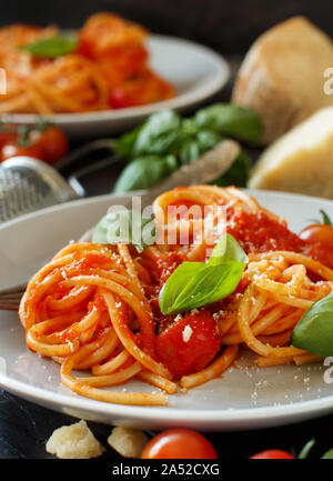 Pasta espagueti con salsa de tomate, albahaca y queso en una mesa de madera Foto de stock