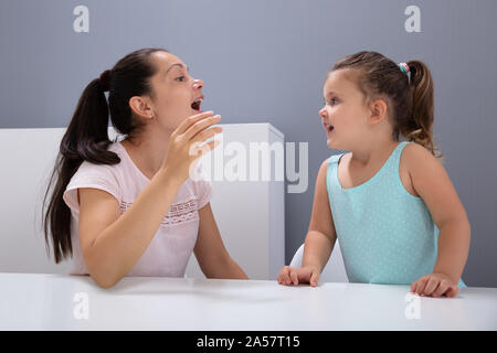 Una hembra atractiva Logopeda ayuda a la niña cómo pronunciar los Sonidos de Office Foto de stock