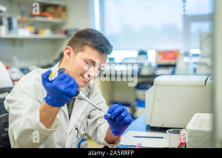 Joven estudiante de ciencias realizando un experimento biotecnológico en laboratorio Foto de stock