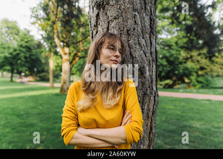 Mujer joven en un árbol en el parque mirando lateralmente