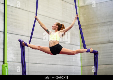 Mujer joven haciendo seda antena en una sala de ejercicios Foto de stock