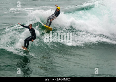 Surfista Senior y un joven jinete compartiendo una ola en Huntington Beach, California, también conocido como Surf City USA, hogar de los EE.UU. Abierto de surf.
