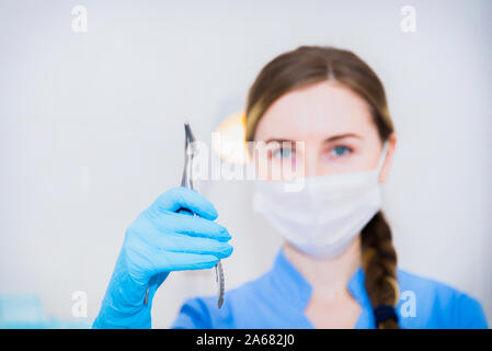 Atractivo femenino doctor en máscara mujer mostrar Thumbs up signo de mano con fondo de hospital Foto de stock