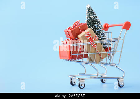 Compras lleno de varias cajas de regalos y un árbol de Navidad sobre fondo azul claro. Concepto de venta de Navidad.