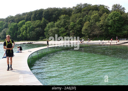 La gente caminando por el puente infinito (Den Uendelige Bro) - muelle de madera con forma de círculo construido sobre un mar de la costa de la Bahía de Aarhus sobre una playa de Varna/Ballehage Playa, creado por el arquitecto Niels Povlsgaard y Johan Gjødes son vistos en Aarhus, Dinamarca, el 30 de julio de 2019 © Michal Fludra / Alamy Live News
