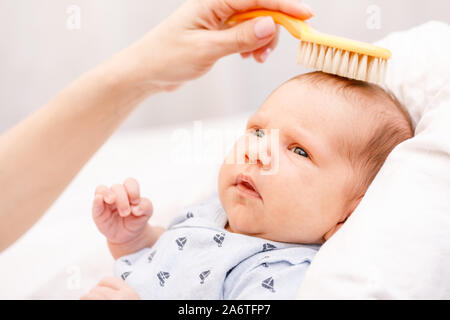 Madre cepillando el cabello de su bebé recién nacido usando un cepillo de  pelo suave para estimular los folículos pilosos del bebé y aumentar el  flujo sanguíneo del cuero cabelludo para un