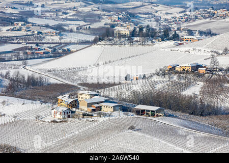 Una vista desde arriba de aldeas y pueblos entre viñedos en las colinas cubiertas de nieve en el Piamonte, Norte de Italia. Foto de stock