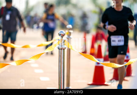 Lujo barricada inoxidable con cuerda cinta amarilla en la carretera en caso de maratón en el punto de llegada. Foto de stock