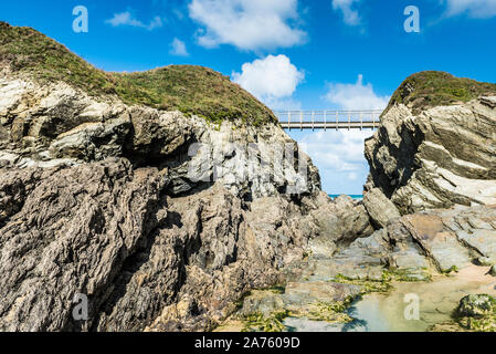 El puente que une la tierra firme con la isla de Porth en Porth Beach en Newquay en Cornualles. Foto de stock