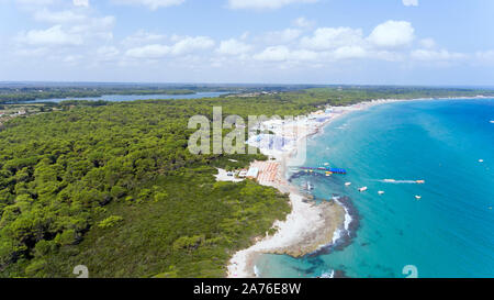 Vista aérea de la playa de arena a lo largo de costa rocosa, árboles de hoja perenne, Baia dei Turchi, en la sureña región italiana de Puglia, sobre las aguas azules del Mar Adriático