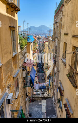 Estrecho callejón en el casco antiguo de Nápoles, con el Vesubio en la espalda Foto de stock