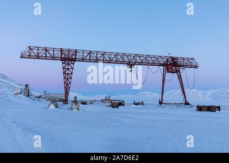 Grúa en el paisaje invernal en Pyramiden. Soviéticos/rusos abandonaron el asentamiento en Svalbard, Noruega. Foto de stock