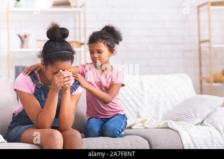 Pequeña muchacha africana reconfortante llorando hermana adolescente con problemas de relación Foto de stock