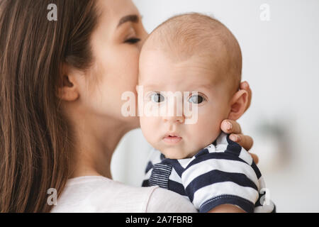 Closeup retrato de madre besar su adorable bebé recién nacido Foto de stock